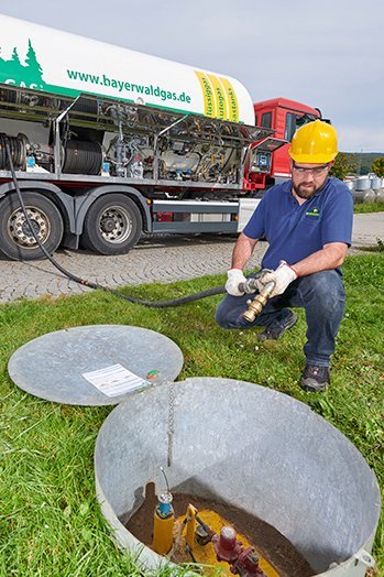 Mitarbeiter füllt unterirdischen Flüssiggasbehälter mit Schlauch vom Tanklastwagen der Firma Bayerwaldgas